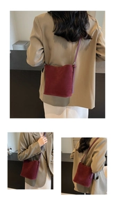 Macro shot of dark red suede bucket bag showing premium texture and shoulder strap