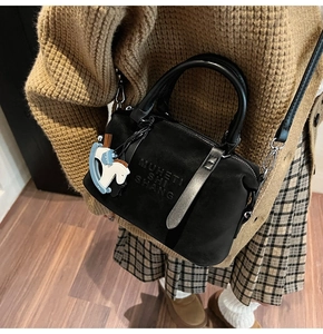 Dettaglio della borsa Boston in pelle scamosciata nera con logo e ciondolo a cavallo