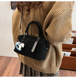 Dettaglio borsa bowling in morbida pelle nera con ciondolo a cavallo e logo inciso