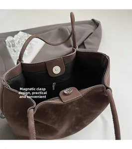 Macro view of dark brown suede tote bag showing magnetic closure and inner zipper pocket