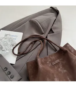 Detail of soft vintage dark brown large tote bag on a blazer with elegant props