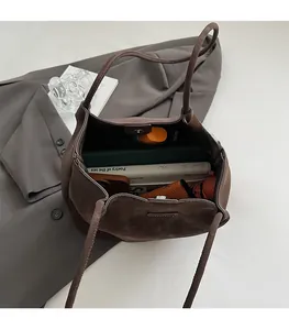 Macro view showing spacious interior of dark brown matte leather tote bag with books