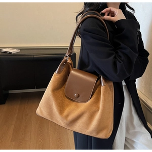 Detail of vintage caramel suede and brown leather shoulder bag with magnetic flap closure
