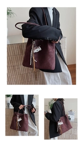 Detailed view of burgundy matte tote bag with cartoon puppy charm and tassel