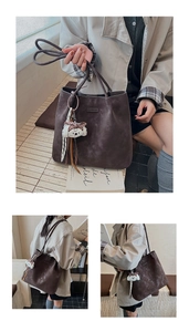 Close-up of large suede tote bag with cartoon puppy charm and metallic logo detail