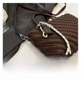 Dettaglio borsa a pieghe marrone scuro con ciondolo cioccolato e decorazione corda