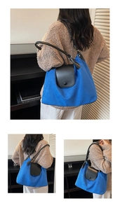 Detail of royal blue tote bag featuring black leather flap and circular button closure