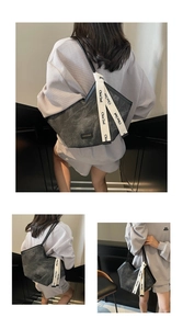 Detail of grey tote bag featuring white logo webbing strap and textured fabric
