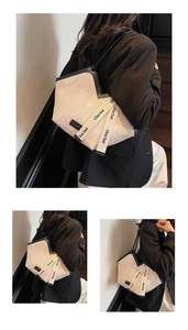 Detail of off-white corduroy tote bag featuring M-shaped opening and black leather piping