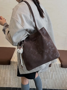 Brown distressed large capacity tote bag with white cat charm worn on shoulder