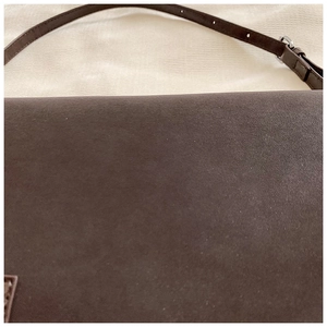 Detail of dark brown matte faux leather shoulder bag with metallic buckle strap