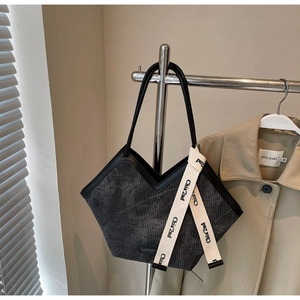 Detail of grey corduroy tote bag with V-shaped opening and decorative letter ribbon