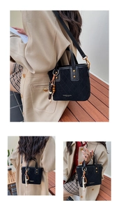 Détail du sac seau noir matelassé avec rivets dorés et pompon perlé décoratif