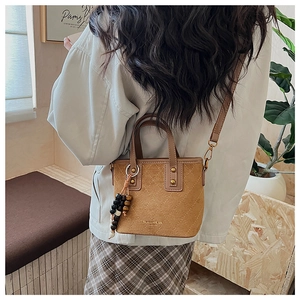 Détail du sac seau en daim fauve avec surpiqûres matelassées et pompon en perles