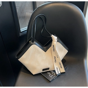 Detail of cream corduroy tote bag with V-shaped design and black leather trim