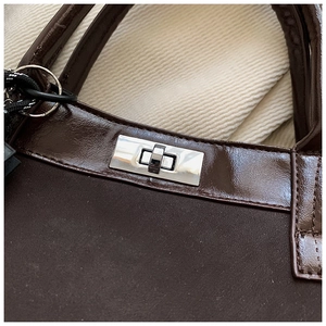 Close-up of vintage brown tote featuring matte texture and silver metal twist lock