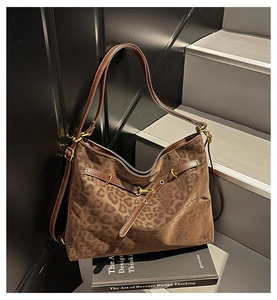 Close-up of leopard print tote bag featuring brown faux suede and leather strap details