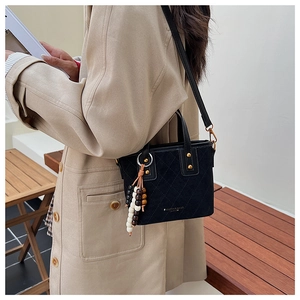 Détail du sac seau noir avec surpiqûres losanges et pompon de perles en bois tricolore