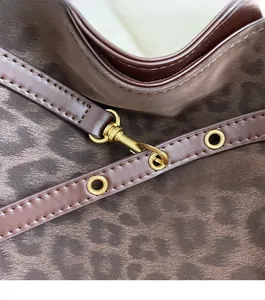 Close-up of leopard print fabric with luxury gold hardware and brown leather strap