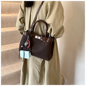 Detail of dark brown canvas and leather handbag with blue coin purse and book charms
