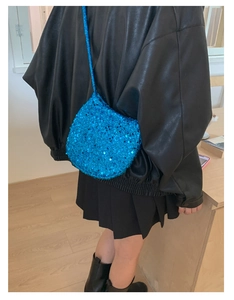 Detail der elektrisch blauen Pailletten-Eimertasche über einer Lederjacke