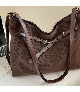 Detail of leopard print tote bag featuring brown leather strap and golden hardware hooks