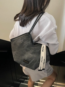 Black textured tote bag with V-shaped opening and long shoulder straps shown on a model