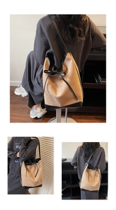 Detail of canvas tote bag with black leather trim and bow tie drawstring closure