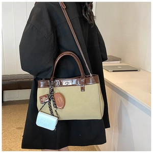 Detail of khaki canvas tote with brown leather handles and decorative MASBI mini pouches