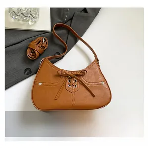 Detailed view of the brown PU leather handbag featuring decorative bow ties and eyelets