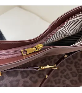 Detail of vintage tote bag showing smooth gold zipper, leopard print, and striped lining