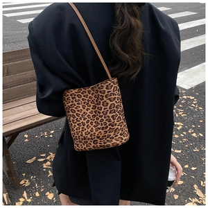 Sac seau à motif léopard tendance porté avec un blazer noir dans un décor urbain chic