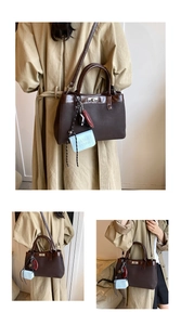 Detail of dark brown matte leather tote bag featuring a blue MASBA charm and metal turn-lock