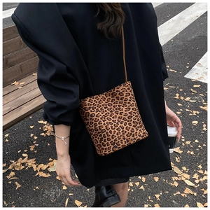 Sac seau à imprimé léopard avec bandoulière marron porté par un mannequin en extérieur