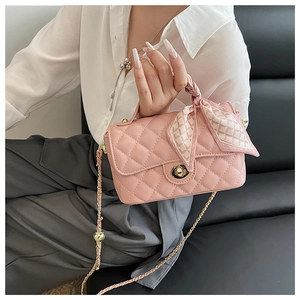 Macro shot of pink quilted crossbody bag with gold chain strap and silk scarf detail