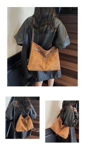 Detail view of large vintage brown tote bag with suede texture and gold metal buckle