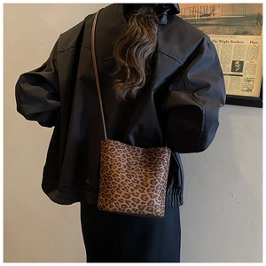 Detail view of leopard print bucket bag worn by model against a vintage background