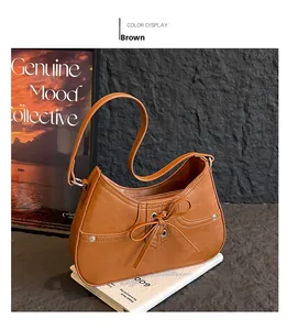 Detail of a brown leather hobo bag with bow tie decoration and white stitching details