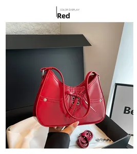Detail view of red glossy bow shoulder bag with metal eyelets in a luxury gift box
