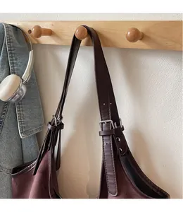 Close-up of the adjustable leather strap and brown suede fabric on a vintage tote bag