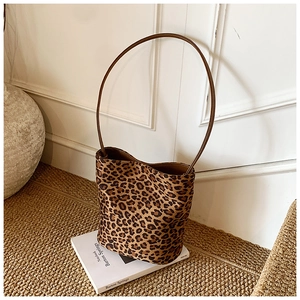 Détail macro du sac seau à motif léopard avec bandoulière marron sur fond rustique