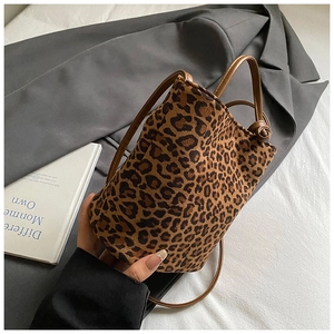 Sac seau imprimé léopard avec poignées en cuir et bandoulière sur un blazer gris