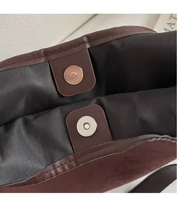 Close-up of magnetic snap closure and durable lining inside a brown tote bag