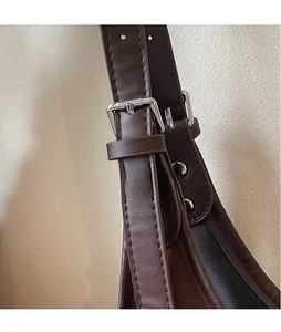Close-up of dark brown PU leather strap with silver metal buckle and white stitching