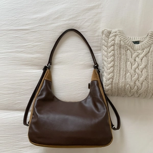 Borsa hobo in pelle cerata marrone con inserti in camoscio kaki su sfondo di tessuto bianco
