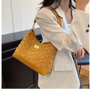 Detalle de bolso bandolera amarillo de felpa y cuero con cierre y herrajes dorados