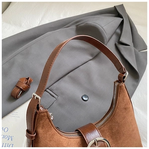 Détail du sac demi-lune en daim marron avec bandoulière en cuir et finitions argentées