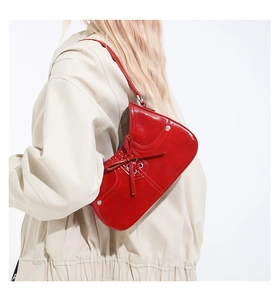 Detailed back view of red patent leather shoulder bag with lace-up bow and metal eyelets