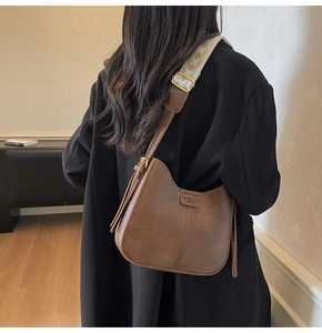 Close-up of retro brown PU leather bucket bag with wide jacquard strap and gold hardware