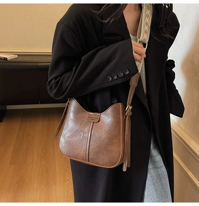 Brown vintage bucket bag detail with retro leather texture and ethnic style woven strap